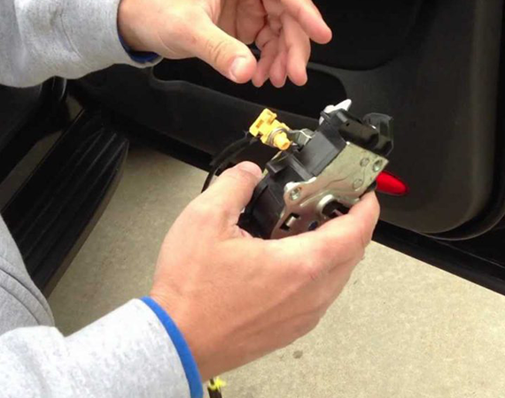 Technician performing car lock repair on a vehicle door